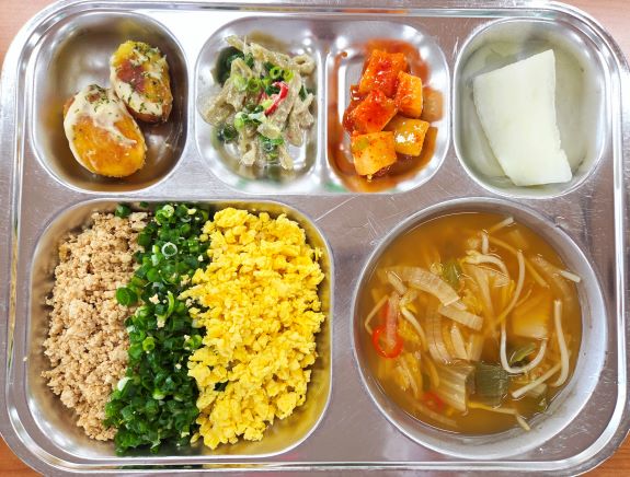    사진은 화동초등학교의 식단 소보로덮밥, 김치콩나물국, 알감자버터구이, 머위대나물, 깍두기, 조각 멜론